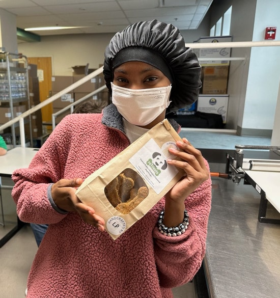 After her first day at work, Ashley shows off a finished bag of dog treats she helped make as part of the reTreats job training program.