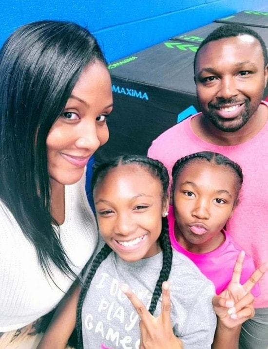A mom takes a selfie with her husband and two young daughters.