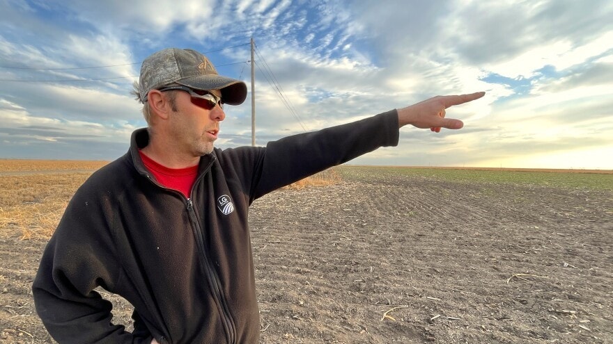 Travis Leonard points across a dry wheat field on his farm in Haskell County. This part of southwest Kansas was one of the state's driest in 2022, with fewer than eight inches of precipitation all year.