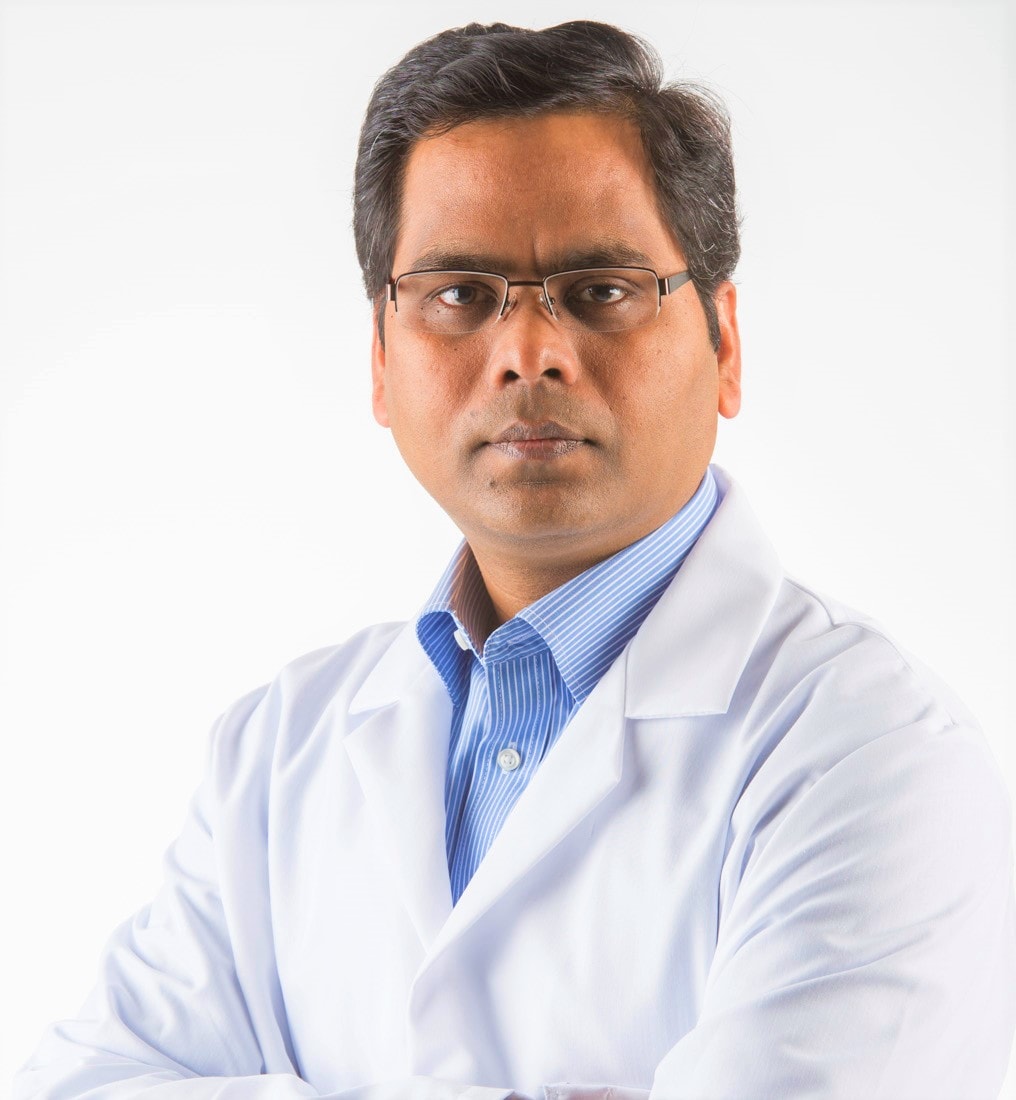 Headshot of a man with glasses and dark hair with a white lab coat.