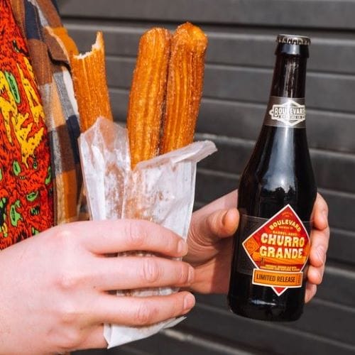 A person holds churros and a bottle of Boulevard Brewing Co.'s new Churro Grande beer.