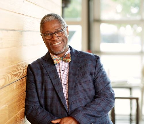 Sly James leaning on a wall and smiling.