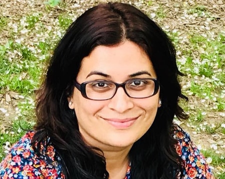 Headshot of a woman in glasses and a floral shirt.