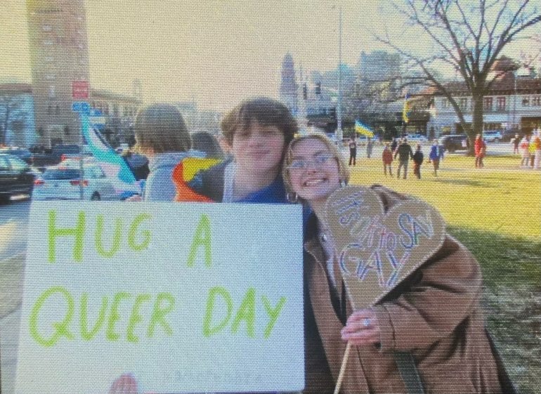 Two high schoolers stand outside of the Country Club Plaza with signs that say "Hug a Queer Day" and "It's OK to Say Gay"during a demonstration protesting SB134. The bill would bar school personnel from discussing gender identity and sexual orientation with students, and require informing the student's parents if they want to go by certain pronouns or wear clothing that aligns with their gender identity.