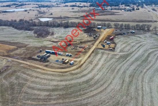 Aerial photo of a field with some shipping containers, cars and a gravel road.