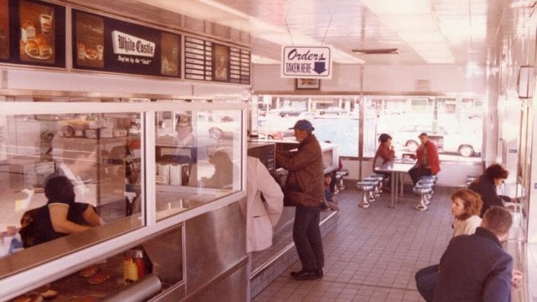 This interior view of White Castle Number 24 in Chicago, with customers placing and waiting for orders, was photographed in April 1983.