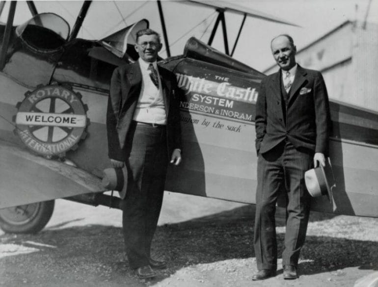 Walt Anderson and Billy Ingram, founders of White Castle Systems, Inc., stand in front of their company airplane. The airplane was purchased in 1927 so they could personally visit all of the White Castle restaurants in their expanding chain.