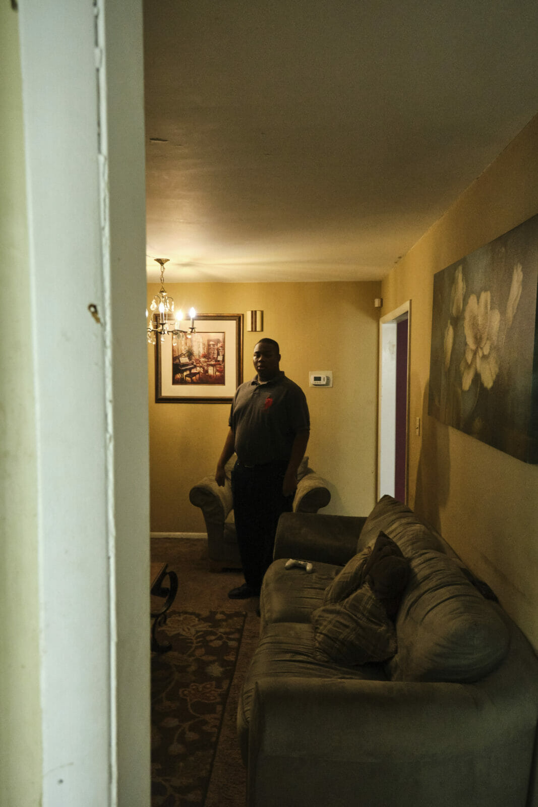 Gerald Mitchell, 17, stands in his living room, a dimly lit room some time at 6 p.m. Gerald Mitchell, who has autism, has a passion for making food. His family hopes to one day fund a food truck operation so he can have a self-sustainable career by the time they're unable to support him financially. (Dominick Williams | Flatland)