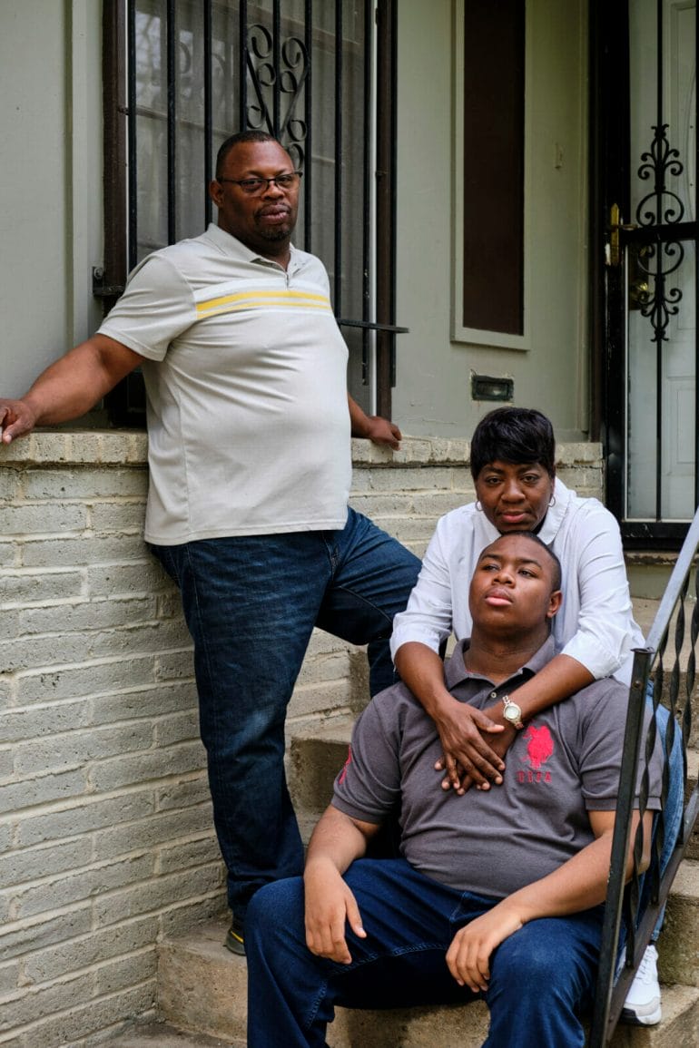A father leans against the exterior wall of his home, while a mom embraces her teen son. The Mitchells are one case of families around the region who say the resources for their kids with disabilities feel out of reach. (Dominick Williams | Flatland)