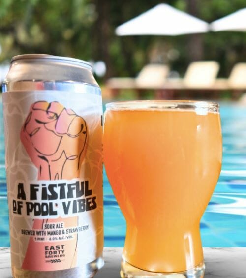 A can and a glass of beer with a swimming pool in the background.