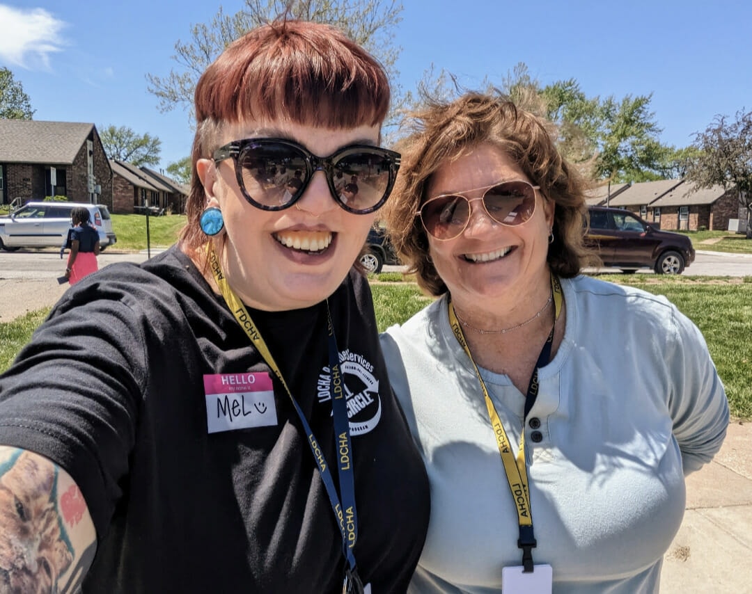 A woman with red bangs, sunglasses and a black shirt with "Full Circle" logo smiles into the camera. Mel Hallenbeck is a Full Circle Youth Program Coordinator with the Lawrence-Douglas County Housing Authority. (Contributed)