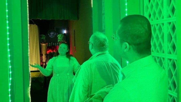 A Dorothy Gale tour guide ushers a group of visitors into the Emerald City at the Land of Oz in Liberal.