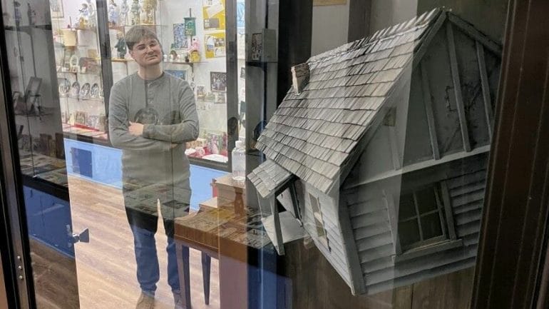 Museum director Nathan Dowell stands next to the actual prop house seen twisting in a tornado in the 1939 film as it hangs suspended in a glass case at the Land of Oz museum in Liberal, Kansas.