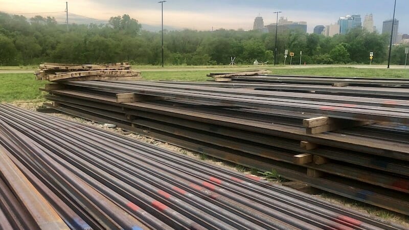 Streetcar rails piled up at the riverfront with the Kansas City skyline in the background.