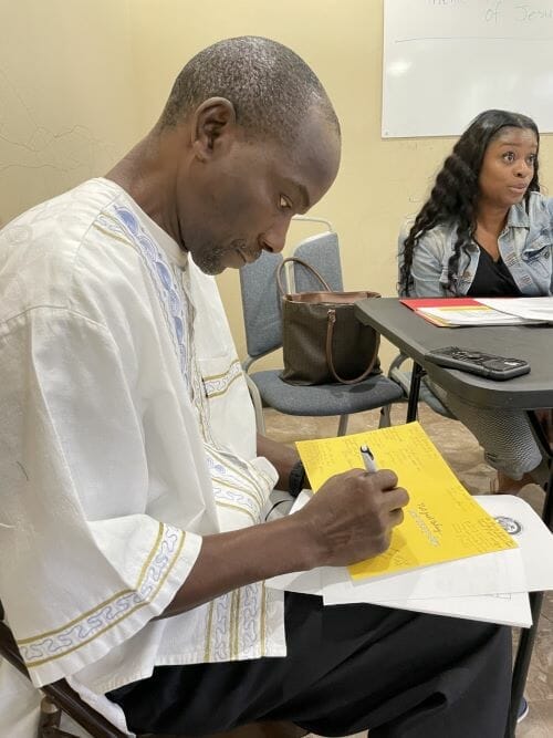 Daniel Masah signs a greeting card from fellow Liberians which will be delivered to shooting survivor Ralph Yarl. The front exclaims “YOU MATTER.”