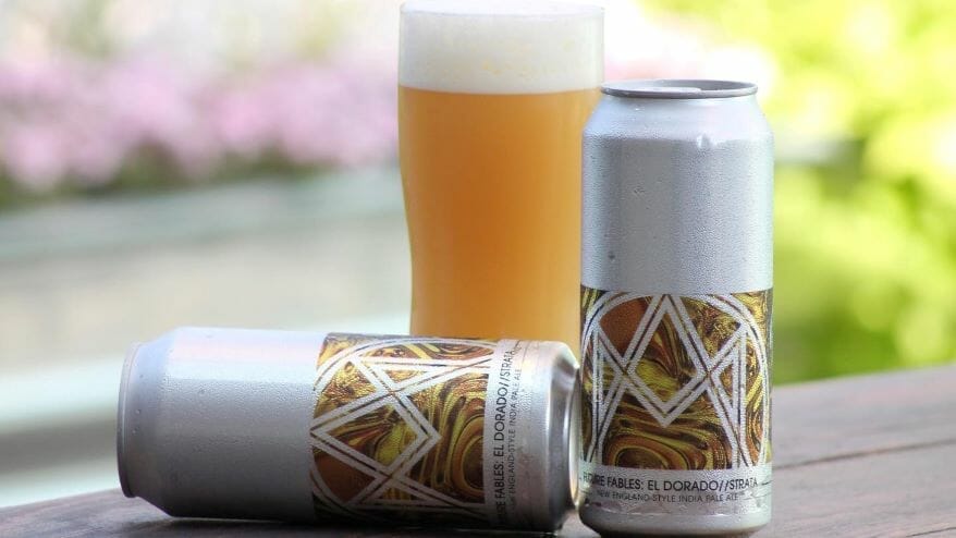 Two cans and a glass of Alma Mader Brewery's new Future Fables beer on a picnic table.
