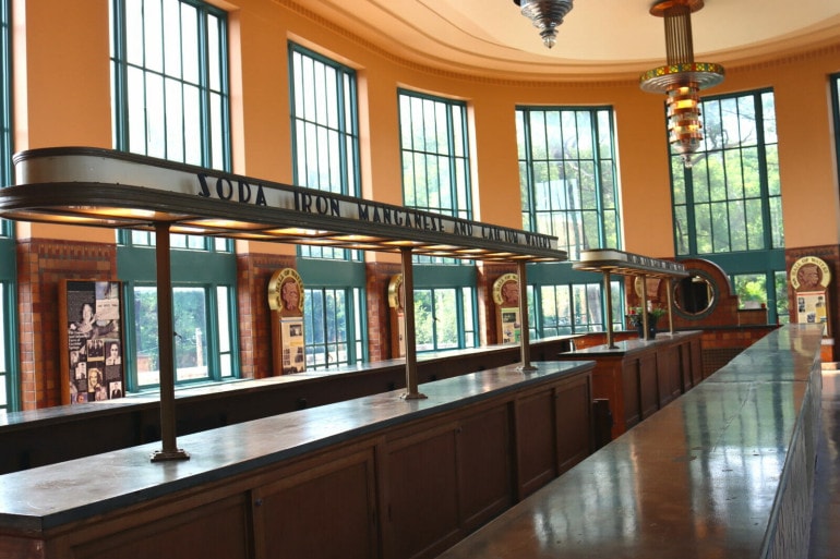 What looks like an old school soda shop bar sits in the middle of an oblong bar. The top of the taps read "Soda, Iron, Manganese and Calcium Waters" Behind are the floor to ceiling windows of the hall of waters 