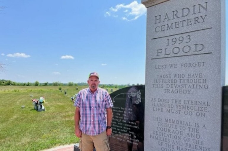 Kevin Carmichael stands next to a monument about the 1993 Flood at the Hardin Cemetery.