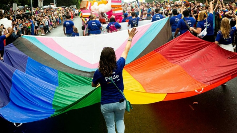 Marchers carry a huge flag during Kansas City's Pride Parade 2023.
