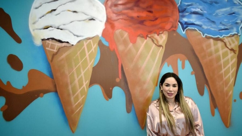 Co-owner Sandy Knight in front of a painting of three ice cream cones at Frutopia.