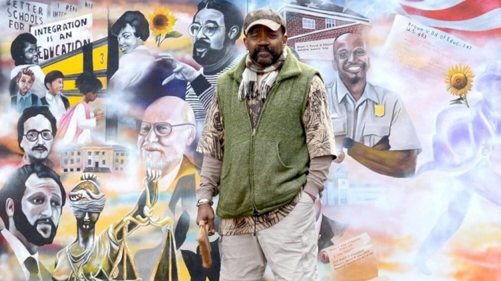 Artist Michael Toombs in front of a mural commemorating the Brown v. Board of Education ruling.