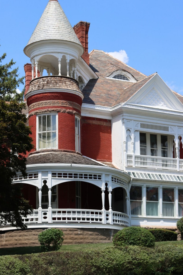 A red and white victorian style mansion with a castle like tower. 