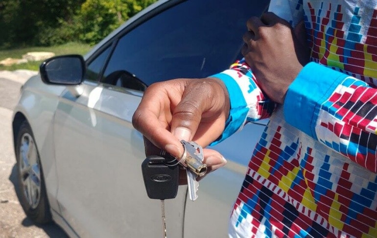Amuri Justin holds the keys to Justin Bilombele's Ford Fusion in Kessler Park on Aug. 19, 2023.