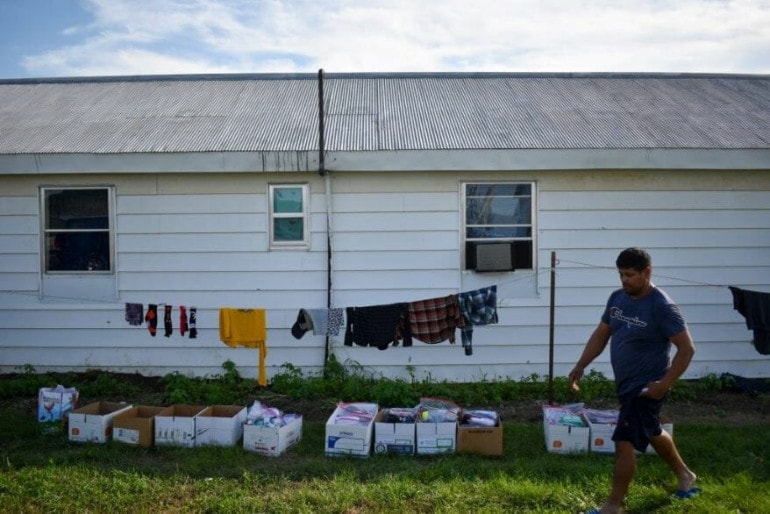 A farmworker walks past boxes of donated supplies from the Migrant Farmworkers Assistance Fund at an apple orchard just outside of Waverly, Missouri.