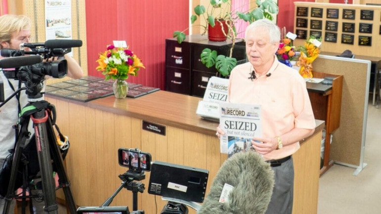 Marion County Record publisher Eric Meyer holds a copy of the Wednesday paper, featuring the headline “SEIZED … but not silence,” during a news conference at the newspaper office.
