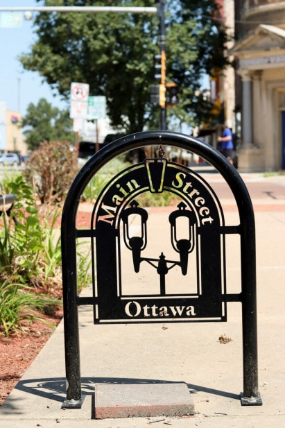 A black, metal bike rack with an inlay that reads "Main Street Ottawa" with a double streetlight drawing.