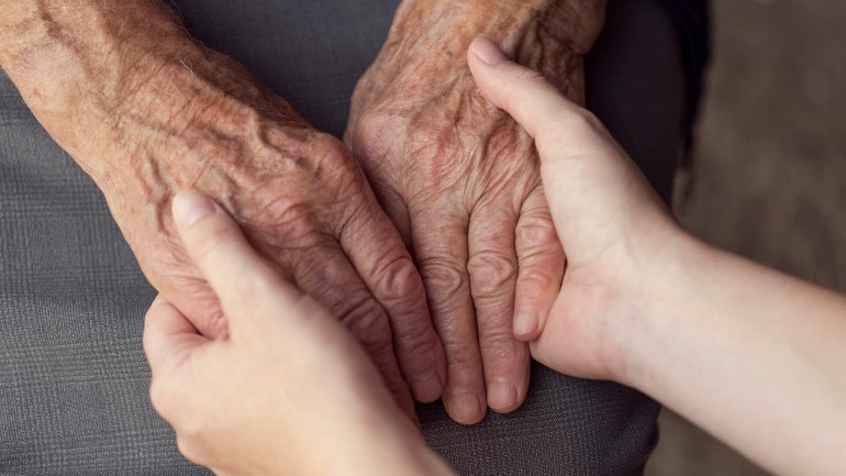 An older adult and a younger person holding hands as they consider long-term care options.