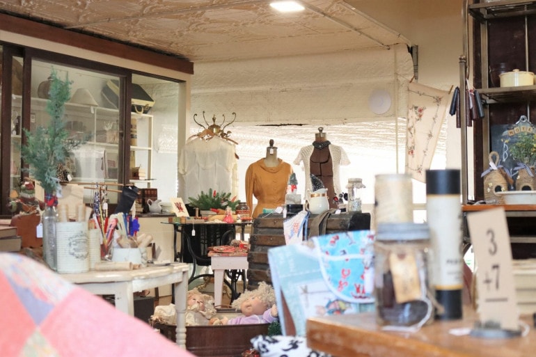 Antique dresses, fabrics, nick knacks and furniture are carefully organized in a shop.