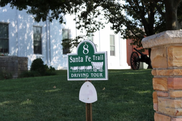 A sign reads "8 Santa Fe Trail Driving Tour" with a picture of a covered wagon and cattle.
