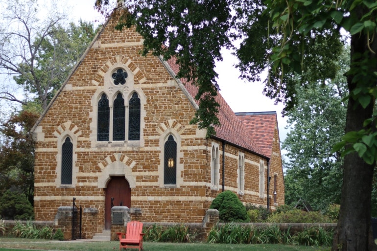 A red stone, small chapel with ornate windows.