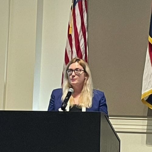 Gavriela Geller speaks at a podium.