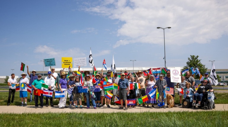A large group of protesters gather with flags representing nations around the world at the Memorial Day NSC protest against nuclear weapons.