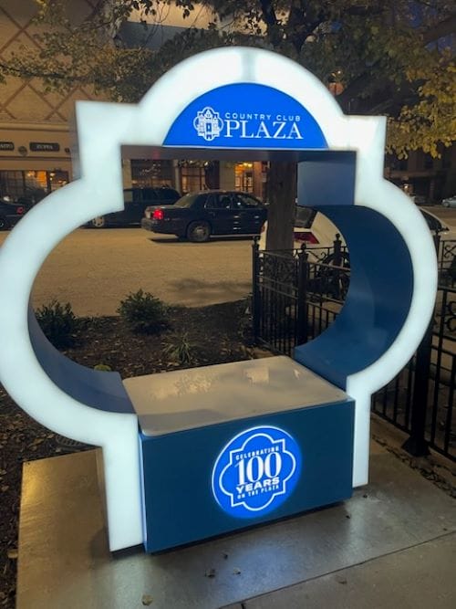 An unmarked Kansas City Police Department patrol car is recognizable passing by a monument marking the Country Club Plaza's centennial.