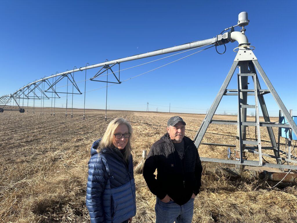 Gina and Marc Gigot stand in front of a center pivot irrigation system on their farm outside of Garden City, Kan.