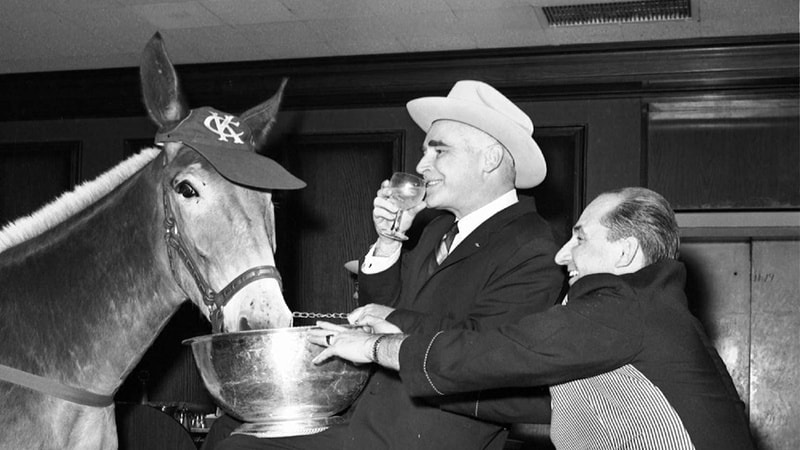 Kansas City Athletics owner Charlie O. Finley, center, watches as bartender John Mundok feeds oats to Athletics mascot ‘Charlie O’ at the Americana Hotel in New York in this April 27, 1965 photo. The Athletics were in town to play against the New York Yankees.