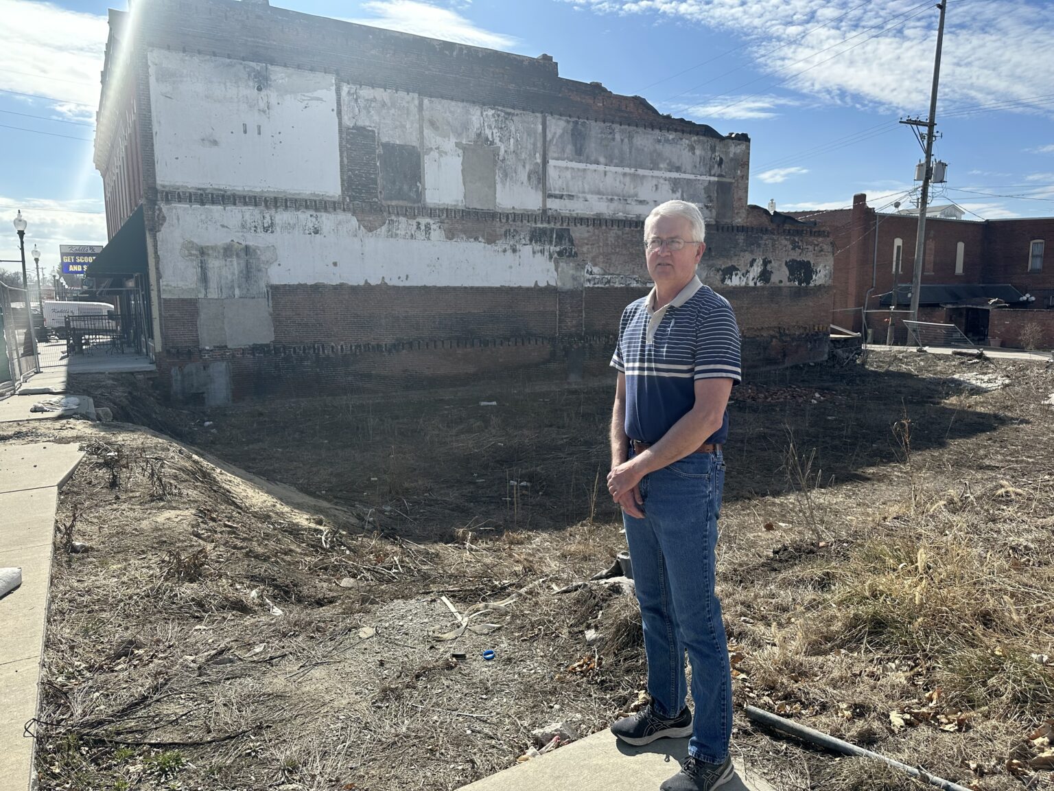Tom Mulholland stands near the site where a 2021 fire destroyed Mulholland Grocery, long a staple of Main Street in Malvern, Iowa.