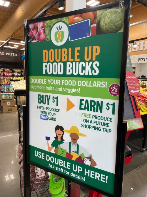 A sign in a grocery store reads "Double Up Food Bucks."