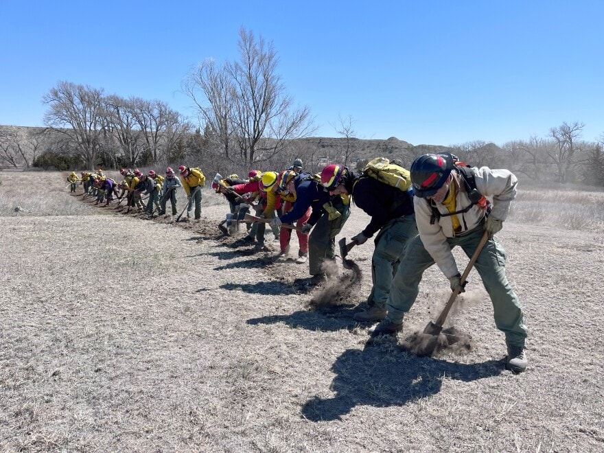 Firefighters and firefighting students practice emergency wildfire response near Scott City by digging a firebreak.
