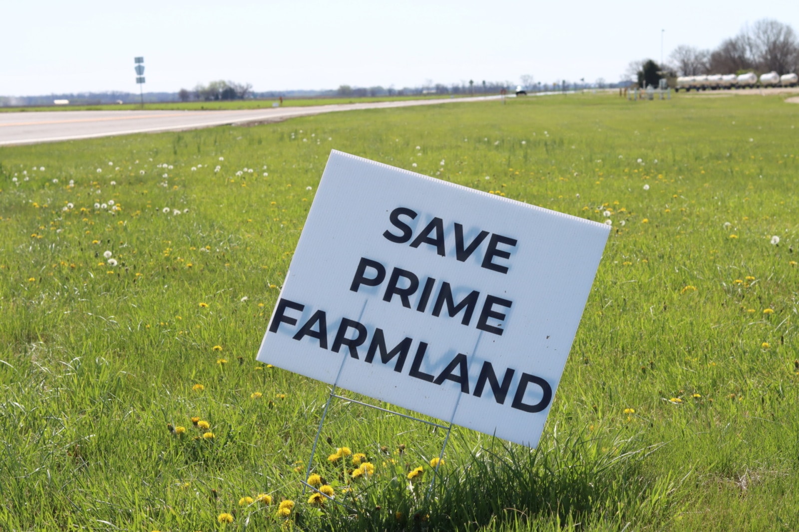 A sign in the grass alongside a highway that reads "Save Prime Farmland"