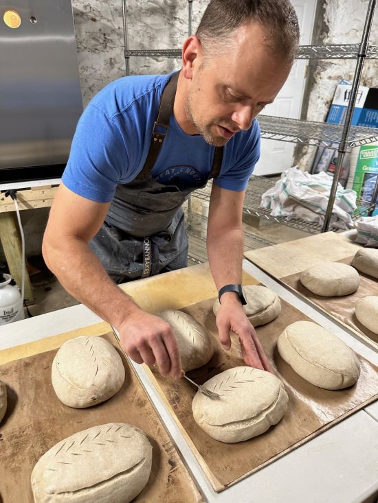 Jon Szajnuk uses a tool to etch designs in loaves of bread.
