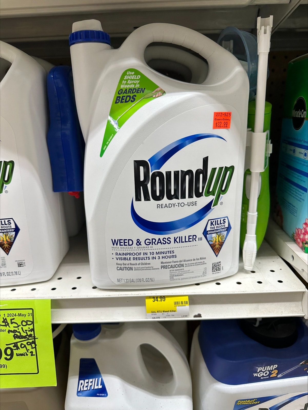 A white bottle blue accents sits on the shelf of a hardware store. the bottle reads "Roudup ready-to-use" "weed and grass killer"