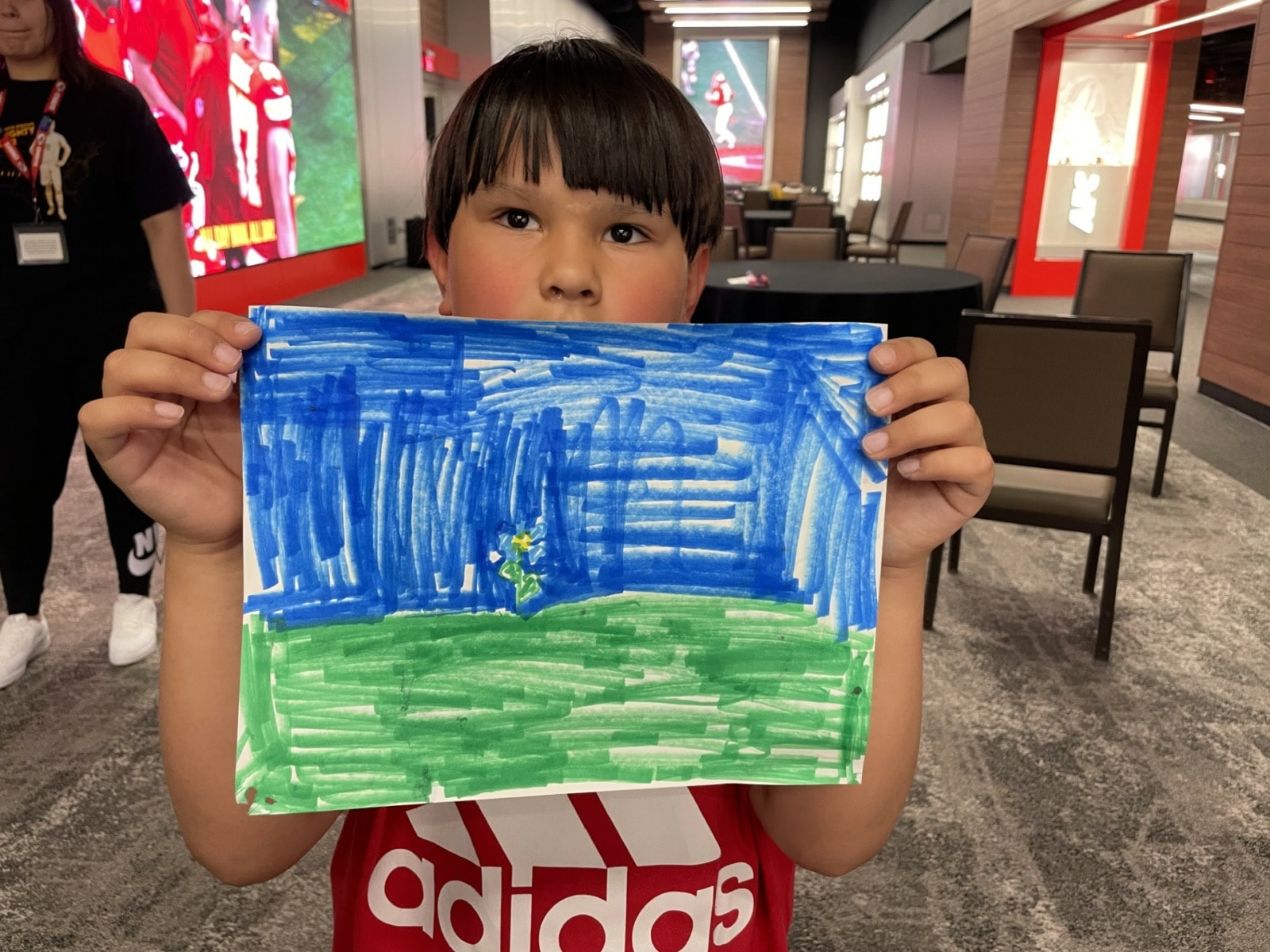 Boy holds blue and green picture