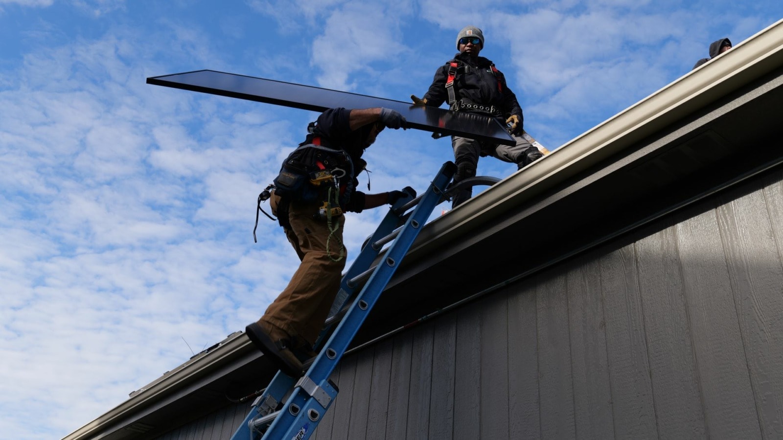 Workers installing solar panels on the roof of a Kansas City area home.