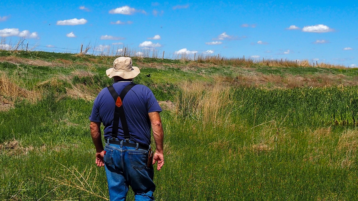 Hugh Brownlee walks by a dry creek bed on his farm near Syracuse, Kansas.