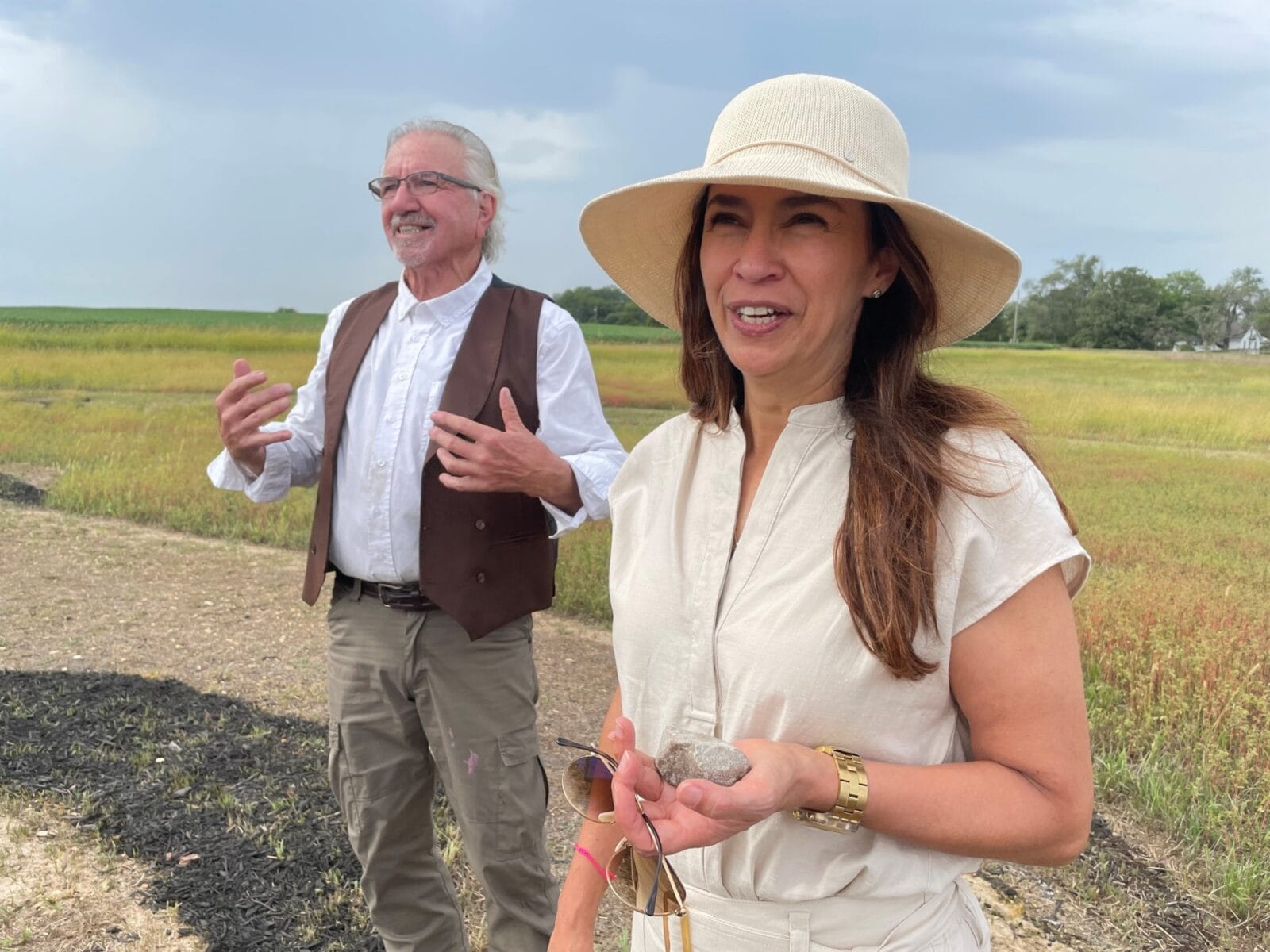 Kansas City-based Mexican Consul Soileh Padilla Mayer prepares to place a stone into the earthwork created by Stan Herd (left) in Linwood, Kansas. (Mary Sanchez | Flatland)